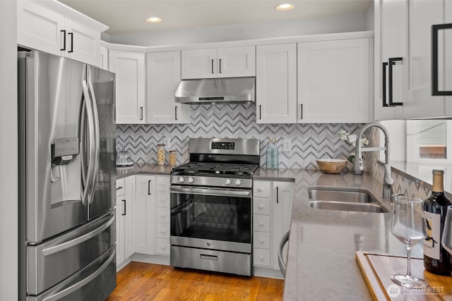 10873 SE 214th Pl, Kent, WA 98031 - kitchen featuring appliances with stainless steel finishes, under cabinet range hood, white cabinetry, decorative backsplash, and light wood-style flooring
