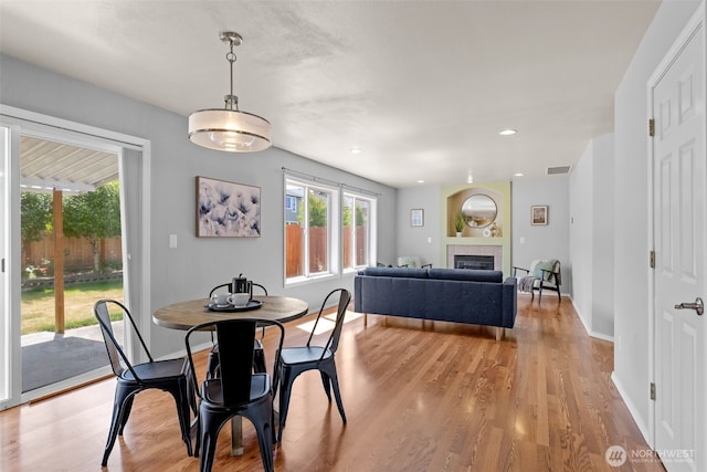 10873 SE 214th Pl, Kent, WA 98031 - dining area with light wood-style flooring, a glass covered fireplace, and recessed lighting
