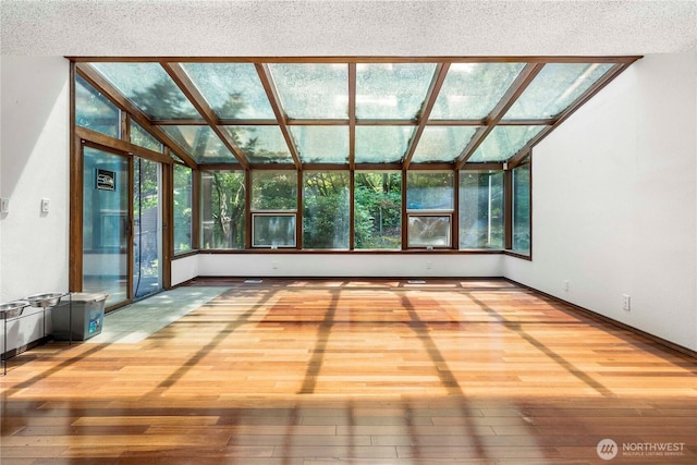 8113 S 121st St, Seattle, WA 98178 - unfurnished living room featuring wood-type flooring, plenty of natural light, vaulted ceiling, a sunroom, and a textured ceiling