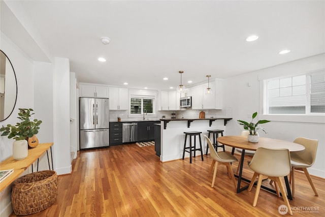 9217 Roosevelt Way NE Unit B, Seattle, WA 98115 - kitchen with stainless steel appliances, backsplash, white cabinetry, a kitchen bar, and a peninsula