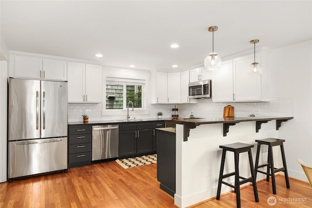 9217 Roosevelt Way NE Unit B, Seattle, WA 98115 - kitchen with stainless steel appliances, white cabinets, a breakfast bar, and recessed lighting