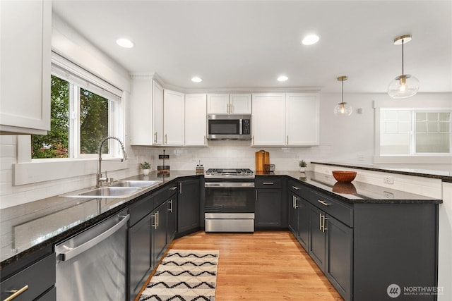 9217 Roosevelt Way NE Unit B, Seattle, WA 98115 - kitchen with stainless steel appliances, white cabinetry, decorative backsplash, light wood finished floors, and a peninsula