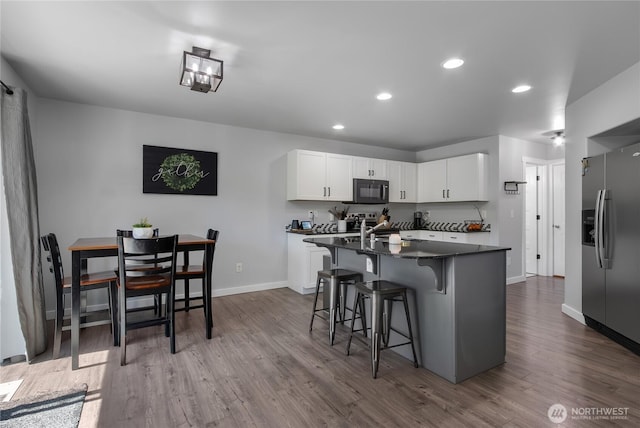 19826 207th Street Ct E, Orting, WA 98360 - kitchen featuring black microwave, dark wood-style floors, stainless steel refrigerator with ice dispenser, a kitchen breakfast bar, and recessed lighting