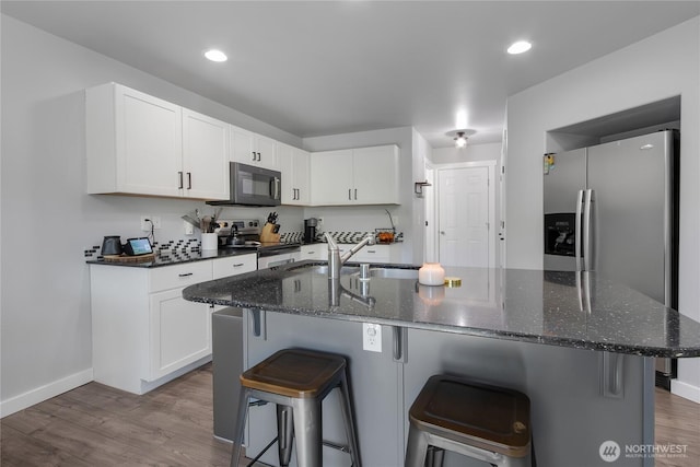 19826 207th Street Ct E, Orting, WA 98360 - kitchen featuring appliances with stainless steel finishes, a kitchen breakfast bar, white cabinetry, dark wood finished floors, and recessed lighting