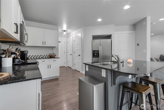 19826 207th Street Ct E, Orting, WA 98360 - kitchen featuring appliances with stainless steel finishes, light wood finished floors, a breakfast bar area, dark stone countertops, and white cabinets