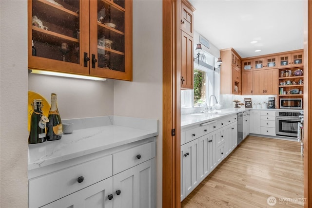 19808 Yew Way, Snohomish, WA 98296 - kitchen featuring appliances with stainless steel finishes, light wood-style floors, glass insert cabinets, light stone counters, and recessed lighting