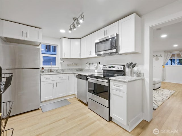 2118 S Sheridan Ave, Tacoma, WA 98405 - kitchen with stainless steel appliances, white cabinetry, light wood finished floors, and light stone counters