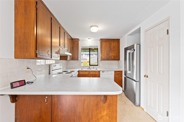 802 39th Pl, Bellingham, WA 98229 - kitchen with white appliances, light countertops, under cabinet range hood, a peninsula, and brown cabinets