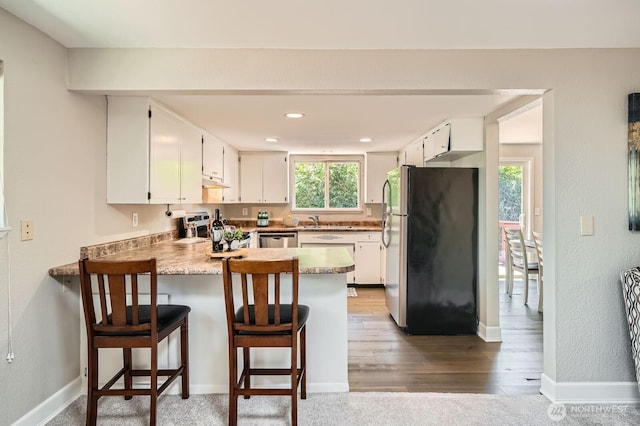13601 SE 141st St, Renton, WA 98059 - kitchen with appliances with stainless steel finishes, a peninsula, under cabinet range hood, wood finished floors, and white cabinets