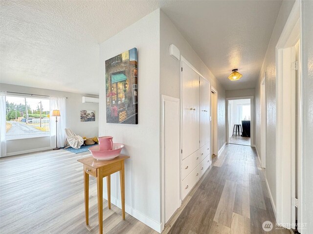 101 E Whidby Ave, Port Angeles, WA 98362 - hallway with a textured ceiling, light wood-style floors, and a wall unit AC