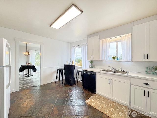 101 E Whidby Ave, Port Angeles, WA 98362 - kitchen featuring dishwasher, freestanding refrigerator, stone tile flooring, and white cabinetry