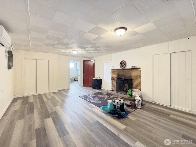 101 E Whidby Ave, Port Angeles, WA 98362 - unfurnished living room featuring wood finished floors, an AC wall unit, and a brick fireplace