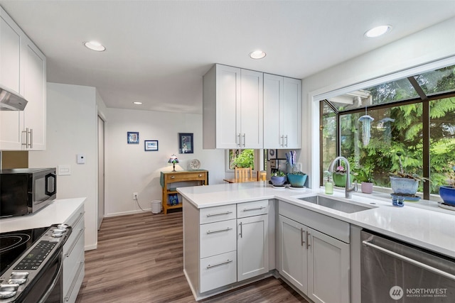 190 Bluffs Dr Unit 1, Port Townsend, WA 98368 - kitchen featuring stainless steel appliances, light countertops, a peninsula, dark wood-style flooring, and recessed lighting