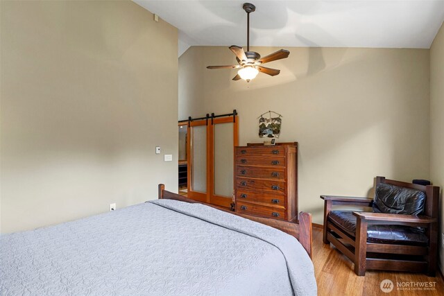 190 Bluffs Dr Unit 1, Port Townsend, WA 98368 - bedroom featuring light wood-style floors, a barn door, a ceiling fan, and high vaulted ceiling