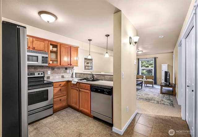 690 32nd St Unit B210, Bellingham, WA 98225 - kitchen featuring appliances with stainless steel finishes, brown cabinetry, light tile patterned flooring, glass insert cabinets, and hanging light fixtures