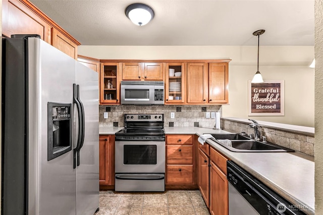 690 32nd St Unit B210, Bellingham, WA 98225 - kitchen featuring appliances with stainless steel finishes, brown cabinets, tasteful backsplash, glass insert cabinets, and light countertops