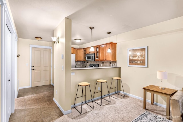 690 32nd St Unit B210, Bellingham, WA 98225 - kitchen featuring stainless steel microwave, brown cabinetry, a kitchen breakfast bar, freestanding refrigerator, and tasteful backsplash