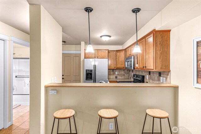 690 32nd St Unit B210, Bellingham, WA 98225 - kitchen featuring stainless steel appliances, tasteful backsplash, a peninsula, a kitchen bar, and hanging light fixtures
