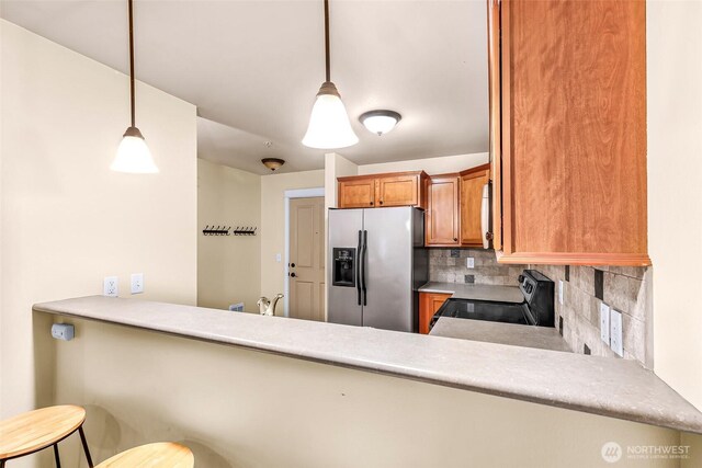 690 32nd St Unit B210, Bellingham, WA 98225 - kitchen featuring stainless steel fridge, black range with electric cooktop, backsplash, hanging light fixtures, and a peninsula