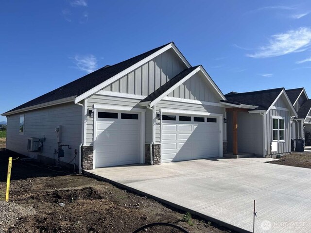 2080 Bowfin Way, Lynden, WA 98264 - view of front of property featuring board and batten siding, a garage, concrete driveway, stone siding, and a shingled roof