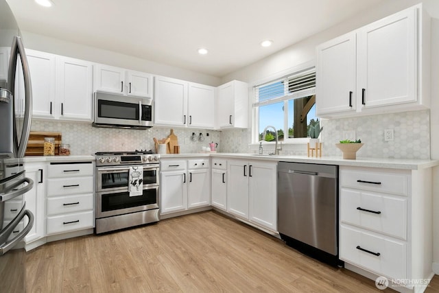 2016 3rd Ct SE, Auburn, WA 98002 - kitchen featuring appliances with stainless steel finishes, light wood-type flooring, decorative backsplash, white cabinetry, and light countertops