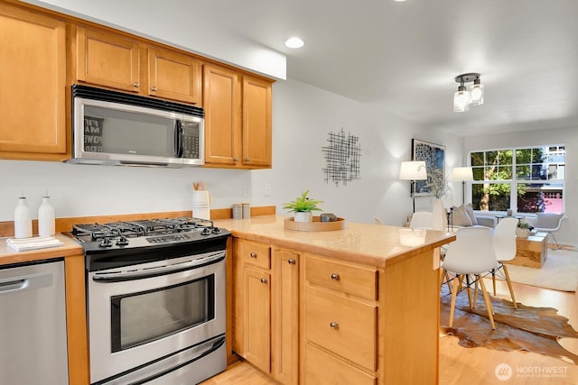 1542 15th Ave S Unit A, Seattle, WA 98144 - kitchen with stainless steel appliances, a peninsula, light countertops, light wood finished floors, and recessed lighting