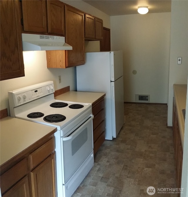 906 S 22nd Ct, Mount Vernon, WA 98274 - kitchen with white appliances, under cabinet range hood, light countertops, stone finish floors, and brown cabinetry