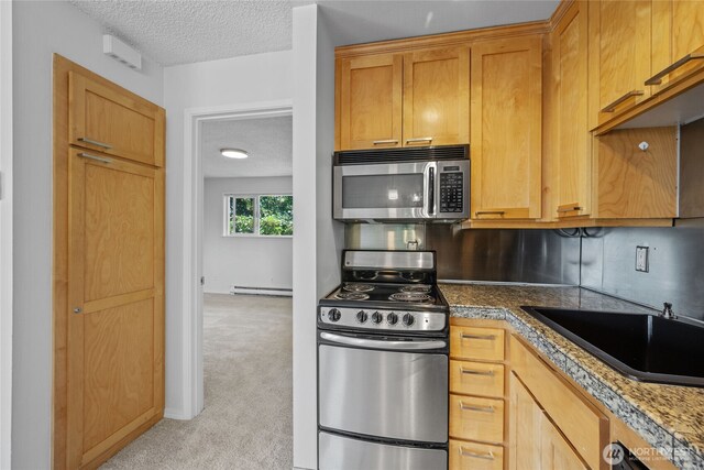604 N 3rd St Unit 8, Tacoma, WA 98403 - kitchen featuring stainless steel appliances, a textured ceiling, light carpet, and a baseboard heating unit