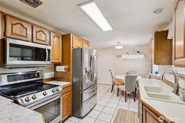 1106 SE 26th St, Auburn, WA 98002 - kitchen with stainless steel appliances, light tile patterned floors, light countertops, and brown cabinetry