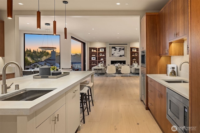 9630 SE 5th St, Bellevue, WA 98004 - kitchen featuring appliances with stainless steel finishes, brown cabinets, hanging light fixtures, light wood-type flooring, and light countertops