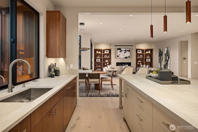 9630 SE 5th St, Bellevue, WA 98004 - kitchen with light countertops, light wood-style floors, a fireplace, decorative light fixtures, and brown cabinetry