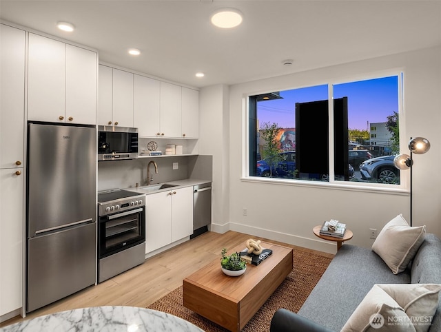 3608 Francis Ave N, Seattle, WA 98103 - kitchen featuring stainless steel appliances, light wood-style flooring, white cabinets, light countertops, and recessed lighting