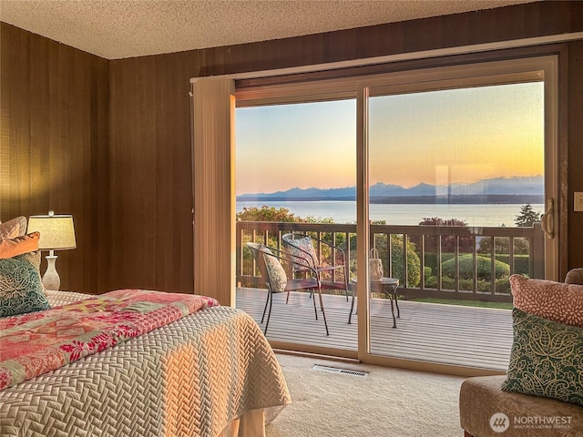 18354 Ridgefield Rd NW, Shoreline, WA 98177 - bedroom featuring carpet floors, access to outside, a water view, wooden walls, and a textured ceiling