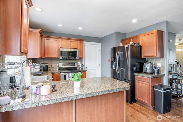 9211 Carys St SE, Yelm, WA 98597 - kitchen featuring appliances with stainless steel finishes, light wood finished floors, backsplash, a peninsula, and recessed lighting