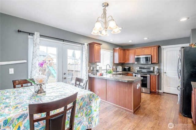 9211 Carys St SE, Yelm, WA 98597 - kitchen featuring appliances with stainless steel finishes, a chandelier, a peninsula, light wood-style flooring, and pendant lighting