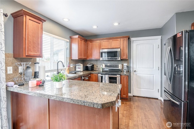 9211 Carys St SE, Yelm, WA 98597 - kitchen with stainless steel appliances, a peninsula, light wood-type flooring, brown cabinets, and recessed lighting