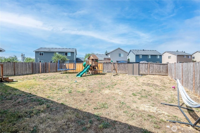 9211 Carys St SE, Yelm, WA 98597 - fenced backyard featuring a trampoline, a playground, and a residential view
