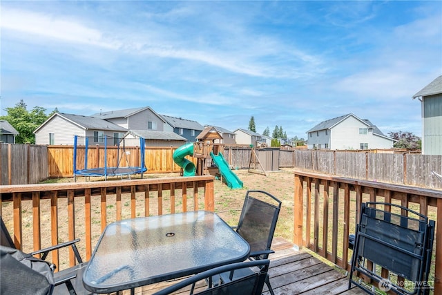 9211 Carys St SE, Yelm, WA 98597 - wooden terrace with a trampoline, a residential view, a playground, outdoor dining area, and a fenced backyard