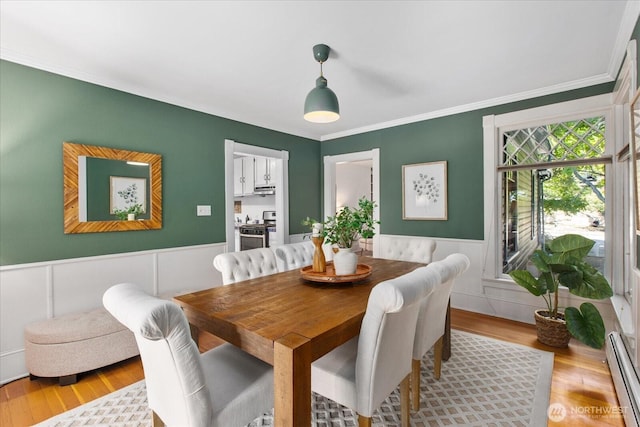 5825 4th Ave NW, Seattle, WA 98107 - dining area featuring baseboard heating, wood finished floors, crown molding, wainscoting, and a decorative wall