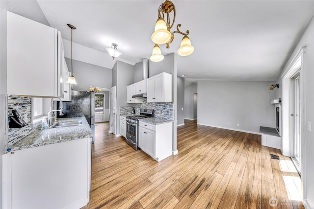 3919 Timothy Ct, Bellingham, WA 98226 - kitchen featuring stainless steel range with gas stovetop, under cabinet range hood, backsplash, vaulted ceiling, and white cabinets