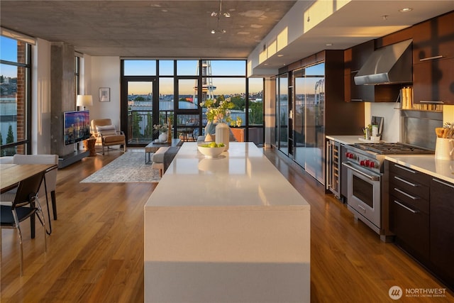 2911 2nd Ave Unit 1120, Seattle, WA 98121 - kitchen with premium stove, expansive windows, wall chimney range hood, modern cabinets, and dark wood-style flooring