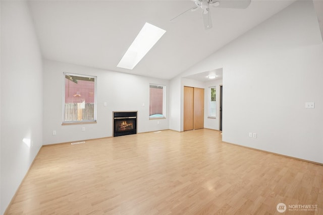 1726 Ann St NE, Olympia, WA 98506 - unfurnished living room featuring wood finished floors, a glass covered fireplace, a skylight, a ceiling fan, and high vaulted ceiling