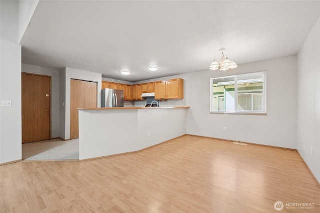 1726 Ann St NE, Olympia, WA 98506 - kitchen with freestanding refrigerator, under cabinet range hood, light wood-type flooring, a peninsula, and a chandelier