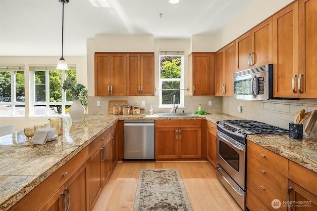 1840 25th Ave NE Unit 210, Issaquah, WA 98029 - kitchen with appliances with stainless steel finishes, brown cabinetry, light wood-type flooring, tasteful backsplash, and pendant lighting