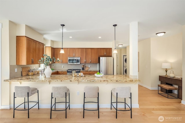 1840 25th Ave NE Unit 210, Issaquah, WA 98029 - kitchen with stainless steel appliances, stacked washer / dryer, a peninsula, backsplash, and light stone counters