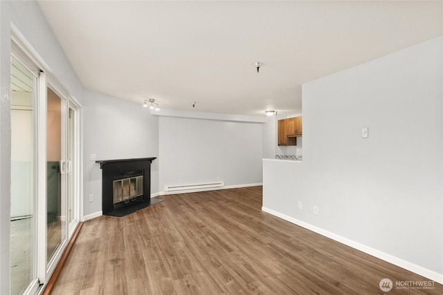 1100AVE NE Harrington Ave NE Unit 211, Renton, WA 98056 - unfurnished living room with a baseboard heating unit, wood finished floors, and a fireplace with flush hearth