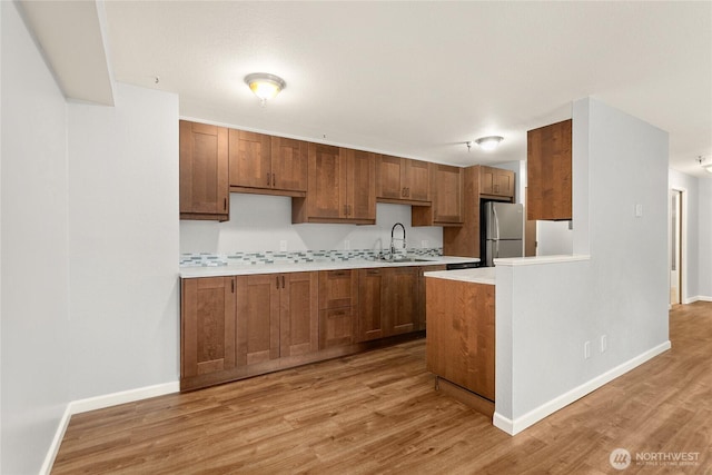 1100AVE NE Harrington Ave NE Unit 211, Renton, WA 98056 - kitchen featuring freestanding refrigerator, light countertops, light wood-style floors, and brown cabinets