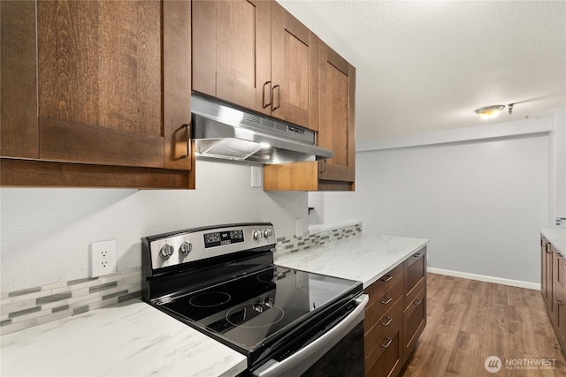1100AVE NE Harrington Ave NE Unit 211, Renton, WA 98056 - kitchen featuring stainless steel range with electric cooktop, under cabinet range hood, wood finished floors, light stone counters, and tasteful backsplash