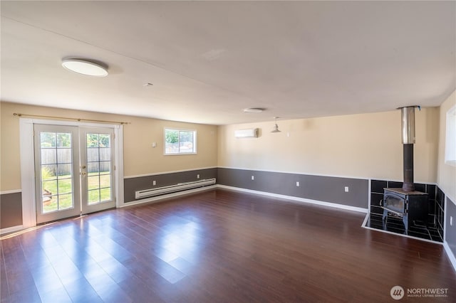 16047 Ashworth Ave N, Shoreline, WA 98133 - unfurnished living room with baseboard heating, wood finished floors, french doors, a wood stove, and an AC wall unit