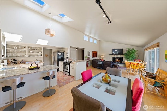 145 Lummi Dr, La Conner, WA 98257 - dining area featuring a skylight, lofted ceiling, track lighting, and light wood-type flooring